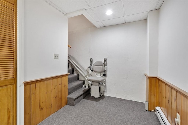 stairway featuring a wainscoted wall, carpet flooring, baseboard heating, and wood walls