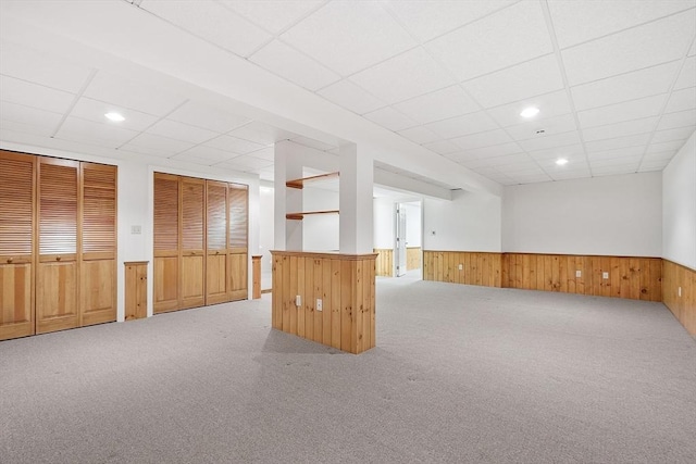spare room with a wainscoted wall, a drop ceiling, carpet flooring, wooden walls, and recessed lighting