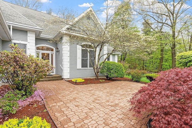 doorway to property with roof with shingles