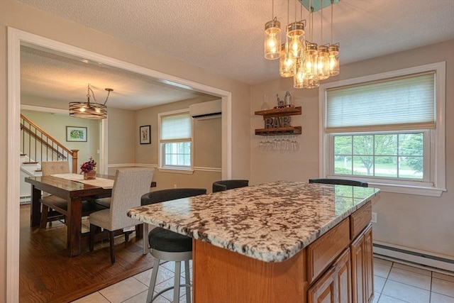 3 Alcorn Rd, Chelmsford, MA 01824 - kitchen featuring a baseboard heating unit, a wall unit AC, light tile patterned floors, a textured ceiling, and a kitchen island
