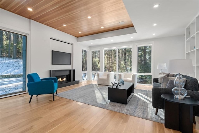 living room featuring a healthy amount of sunlight, light hardwood / wood-style floors, and wooden ceiling