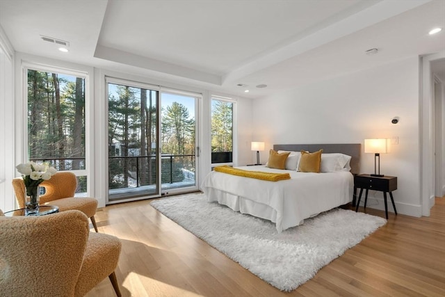 bedroom featuring access to exterior, light hardwood / wood-style floors, and multiple windows