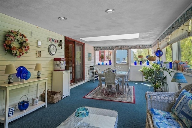 carpeted dining room featuring a textured ceiling, a skylight, and wooden walls