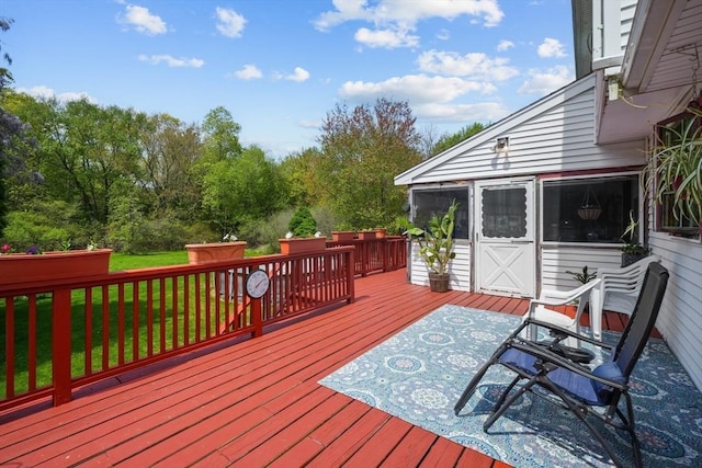 deck featuring a sunroom and a yard