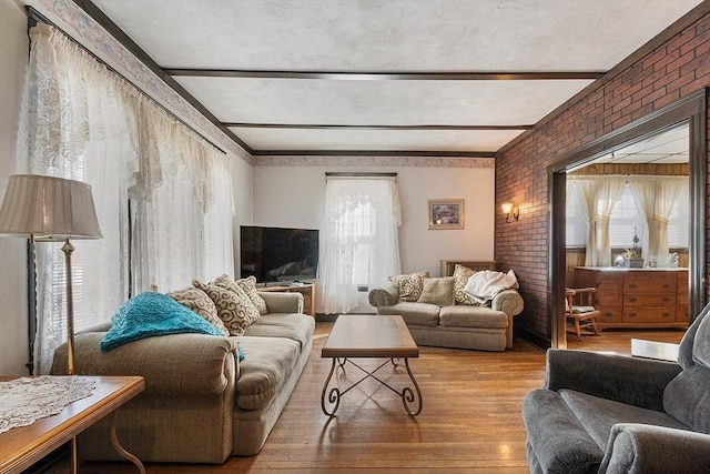 living area with brick wall, beam ceiling, and light wood-style flooring