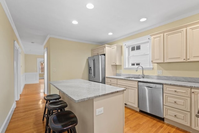 kitchen with a kitchen bar, appliances with stainless steel finishes, light stone countertops, sink, and a center island