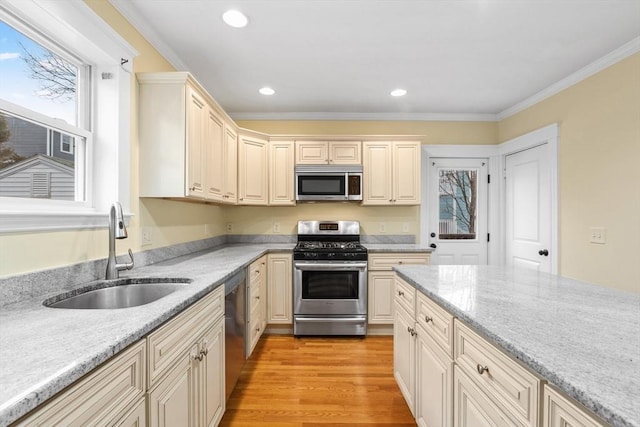 kitchen with sink, stainless steel appliances, light hardwood / wood-style flooring, crown molding, and cream cabinets