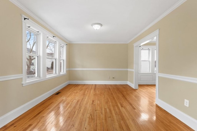 spare room featuring light hardwood / wood-style flooring, a wealth of natural light, and ornamental molding