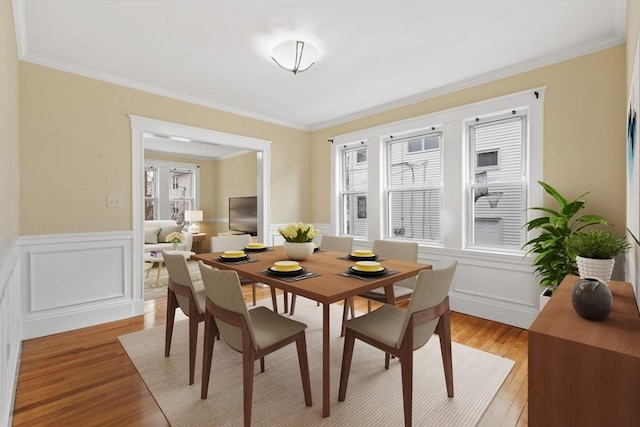 dining space featuring a healthy amount of sunlight, light wood-type flooring, and ornamental molding