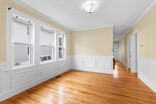 empty room featuring plenty of natural light, ornamental molding, and light hardwood / wood-style flooring