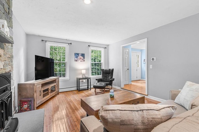 31 Alexander Rd, Hopkinton, MA 01748 - living area with a baseboard heating unit, light wood-style flooring, a wood stove, and baseboards