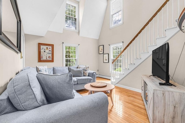 31 Alexander Rd, Hopkinton, MA 01748 - living area featuring a baseboard heating unit, stairs, light wood-style flooring, a towering ceiling, and baseboards