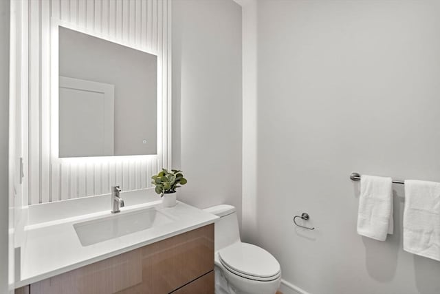 bathroom featuring vanity, toilet, and baseboards