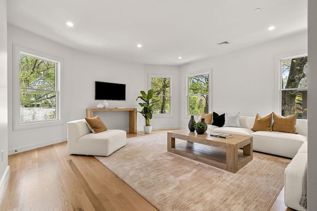 living area featuring healthy amount of natural light, light wood-type flooring, recessed lighting, and baseboards