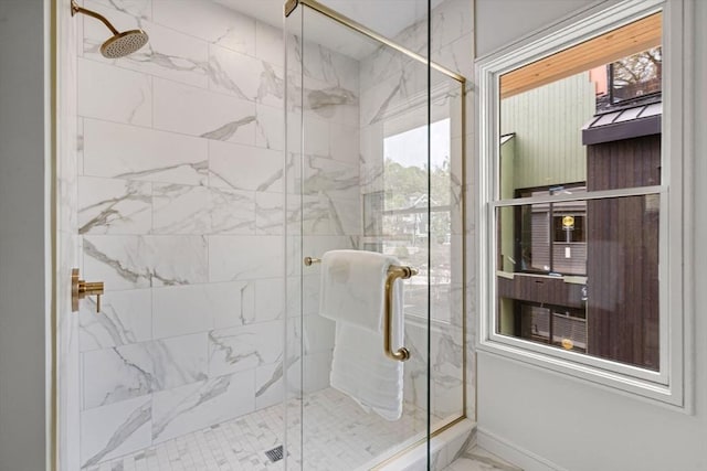 full bathroom featuring marble look tile flooring, a shower stall, and baseboards