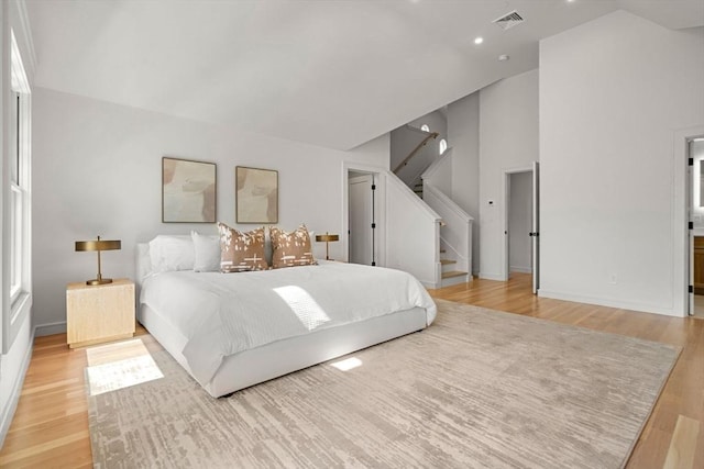 bedroom with light wood-style flooring, high vaulted ceiling, baseboards, and recessed lighting