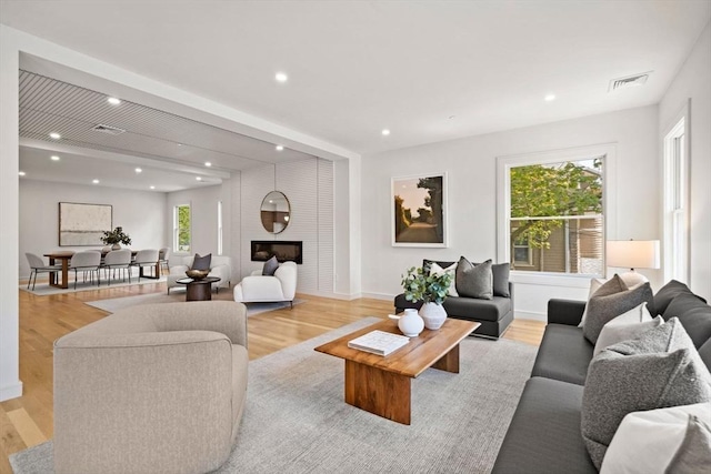 living area with recessed lighting, light wood-style flooring, baseboards, and a large fireplace
