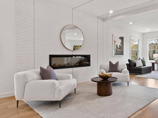 living room featuring wood finished floors, a glass covered fireplace, baseboards, and recessed lighting