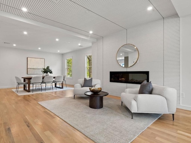 living area featuring baseboards, light wood-type flooring, recessed lighting, and a fireplace