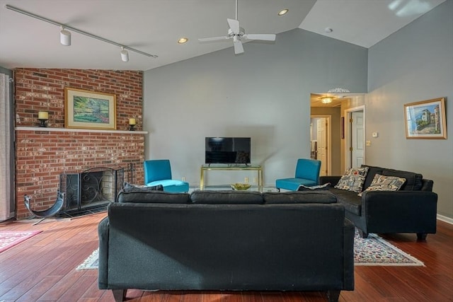 living room featuring a fireplace, rail lighting, hardwood / wood-style floors, and vaulted ceiling