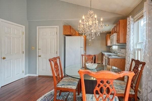 dining area with a chandelier, sink, dark wood-type flooring, and vaulted ceiling