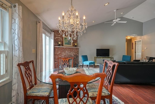 dining room with a fireplace, ceiling fan with notable chandelier, hardwood / wood-style flooring, and lofted ceiling