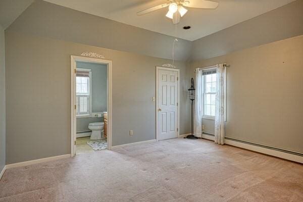 spare room with a baseboard heating unit, light colored carpet, ceiling fan, and a healthy amount of sunlight