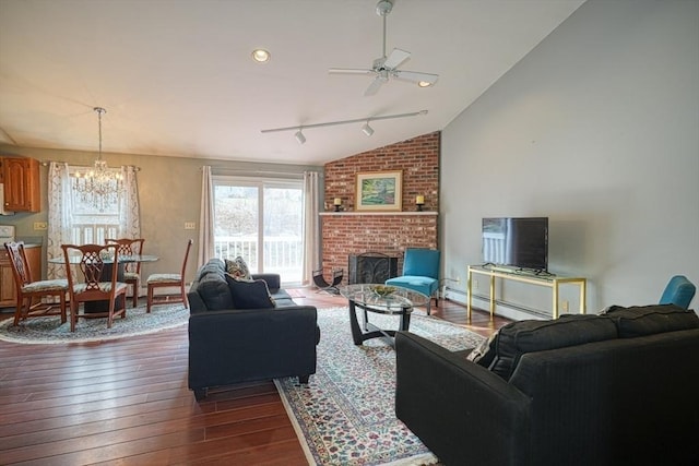 living room featuring lofted ceiling, ceiling fan with notable chandelier, a brick fireplace, dark hardwood / wood-style floors, and baseboard heating