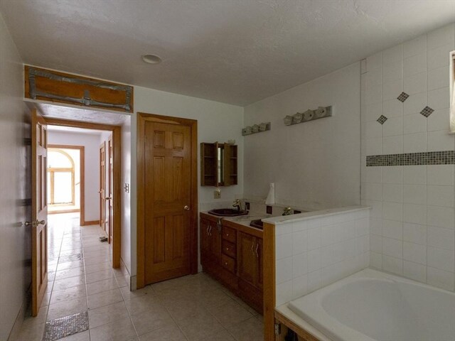 bathroom featuring a tub to relax in, vanity, tile patterned flooring, and a textured ceiling