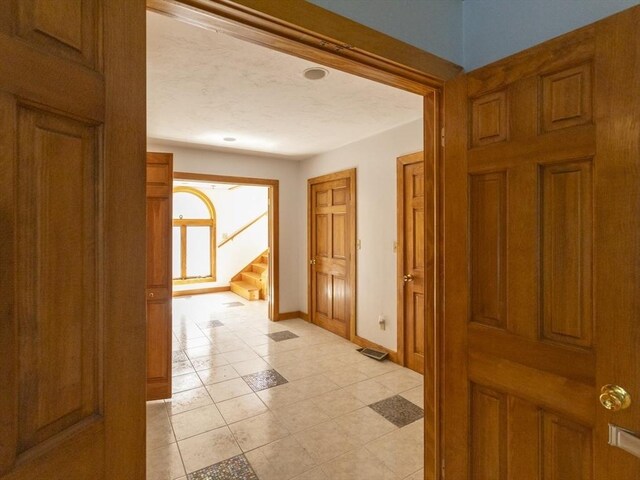 hallway featuring a textured ceiling and light tile patterned flooring