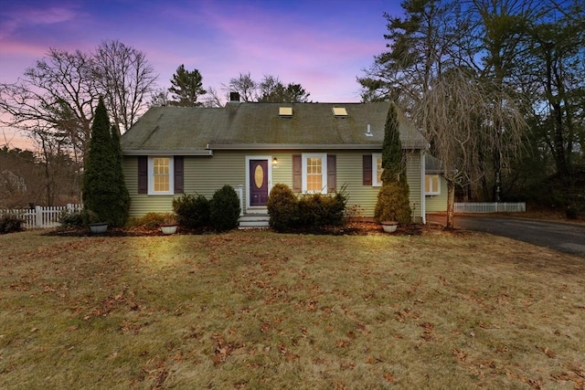 cape cod-style house with a yard and fence