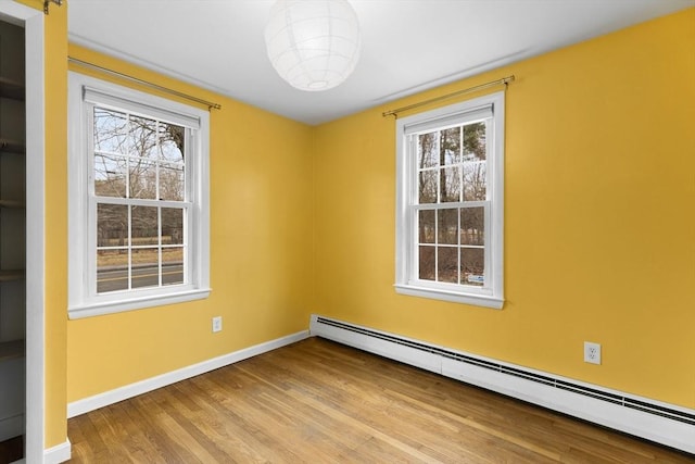 spare room featuring baseboards, baseboard heating, and wood finished floors