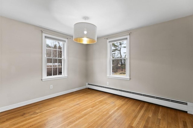 unfurnished room with a baseboard radiator, wood-type flooring, and baseboards