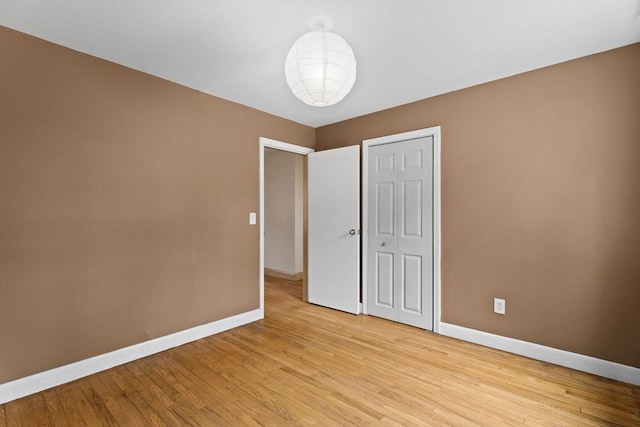 unfurnished bedroom with light wood-style floors, baseboards, and a closet