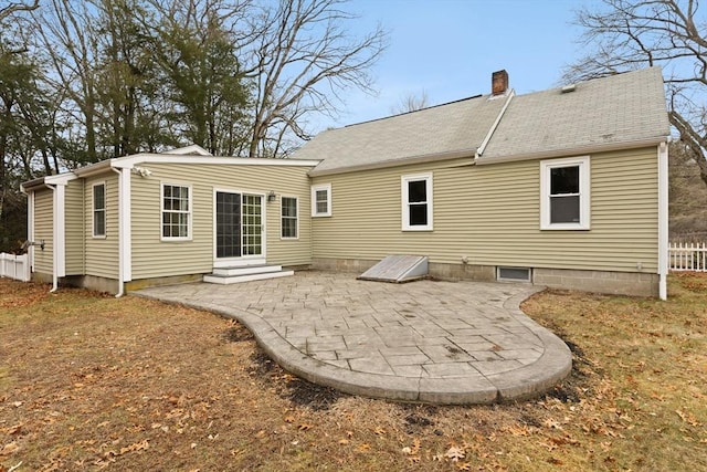 rear view of property with fence, entry steps, a chimney, and a patio area