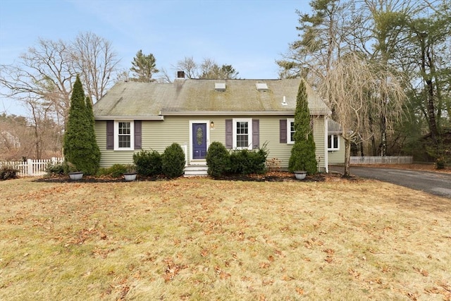 cape cod-style house featuring a front lawn and fence