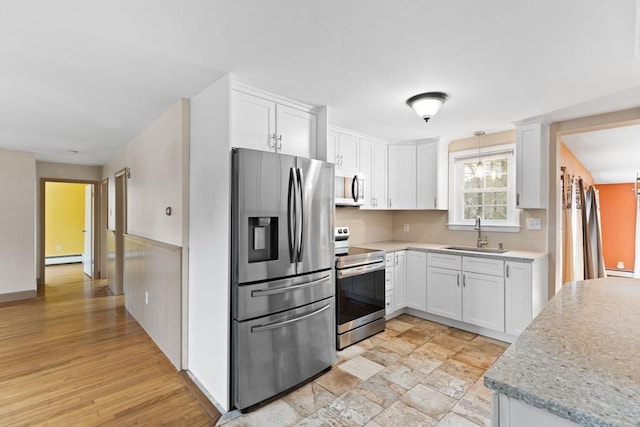 kitchen with a sink, a baseboard heating unit, stainless steel appliances, white cabinetry, and a baseboard radiator