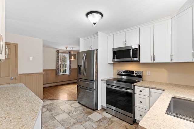 kitchen featuring a baseboard radiator, stainless steel appliances, light countertops, white cabinets, and wainscoting