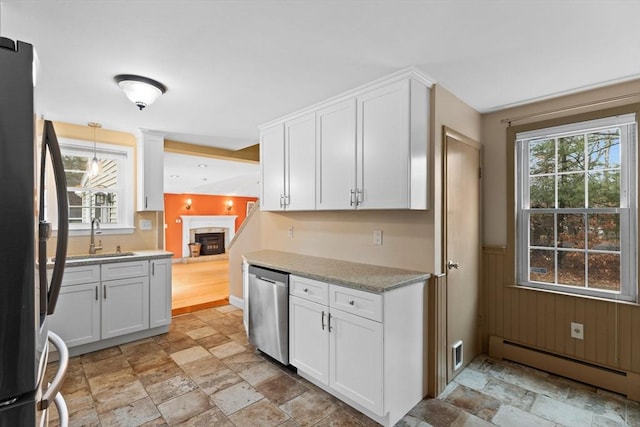 kitchen with stone finish flooring, white cabinetry, freestanding refrigerator, baseboard heating, and dishwasher