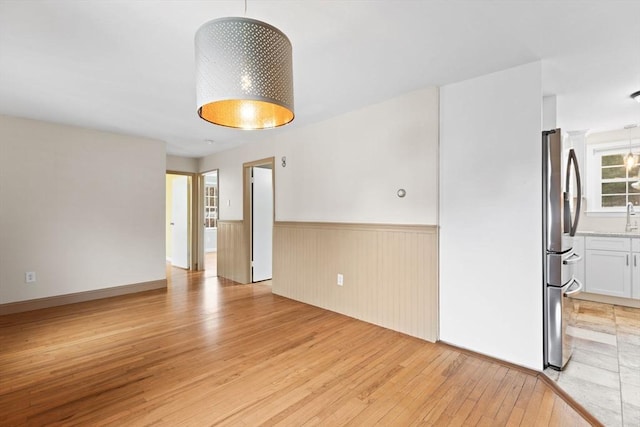 spare room with a wainscoted wall and light wood finished floors