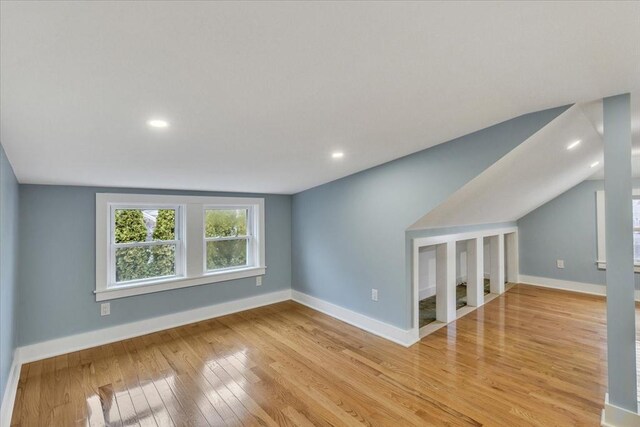 interior space with light wood-type flooring, baseboards, and vaulted ceiling