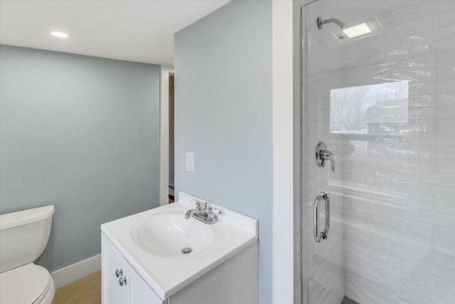 bathroom with a shower stall, toilet, vanity, and baseboards