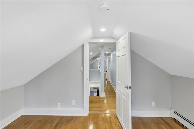 additional living space with a baseboard radiator, baseboards, wood finished floors, and vaulted ceiling