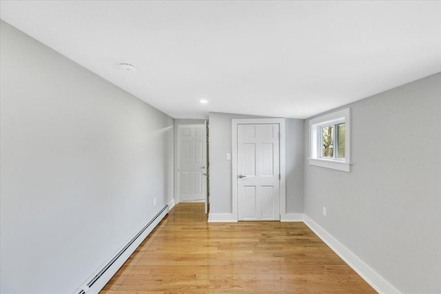 unfurnished bedroom featuring baseboard heating, light wood-type flooring, and baseboards