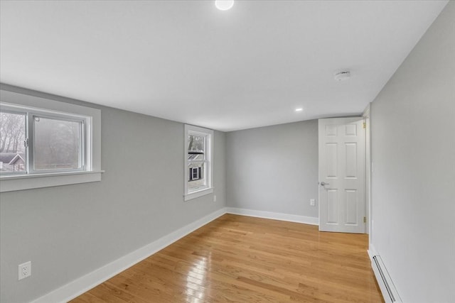 spare room featuring baseboards, light wood-type flooring, and a baseboard radiator