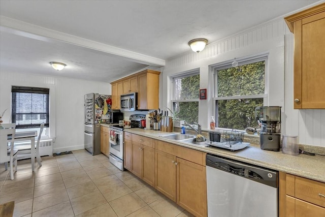 kitchen featuring baseboards, light tile patterned flooring, a sink, stainless steel appliances, and light countertops