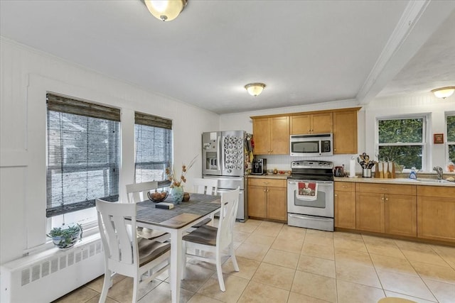 kitchen featuring a healthy amount of sunlight, stainless steel appliances, light countertops, and ornamental molding