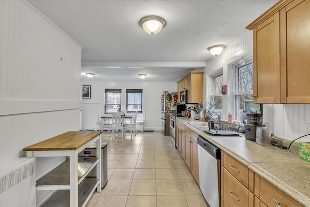 kitchen featuring light tile patterned flooring, brown cabinets, appliances with stainless steel finishes, and radiator