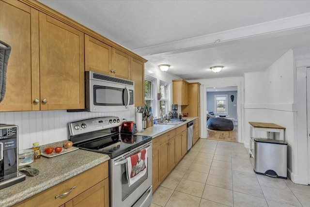 kitchen with light tile patterned floors, stainless steel appliances, brown cabinetry, and light countertops