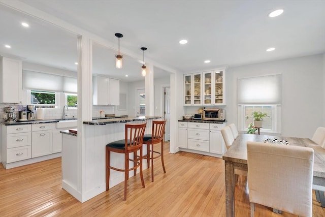 kitchen with white cabinets, dark countertops, a breakfast bar area, tasteful backsplash, and recessed lighting